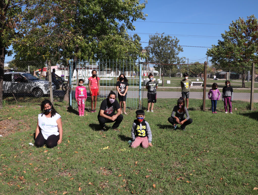 Un grupo de niñes del consejo sentados en el patio del centro comunitario. 